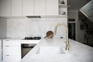 a modern kitchen, focused on the kitchen sink with a brass faucet
