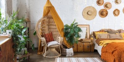 A bohemian-inspired bedroom with natural materials and neutral colors. There's a hanging egg chair in the corner.