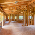 A custom home is in the beginning stages. There is wood, wiring, and planks, all exposed due to the lack of drywall.