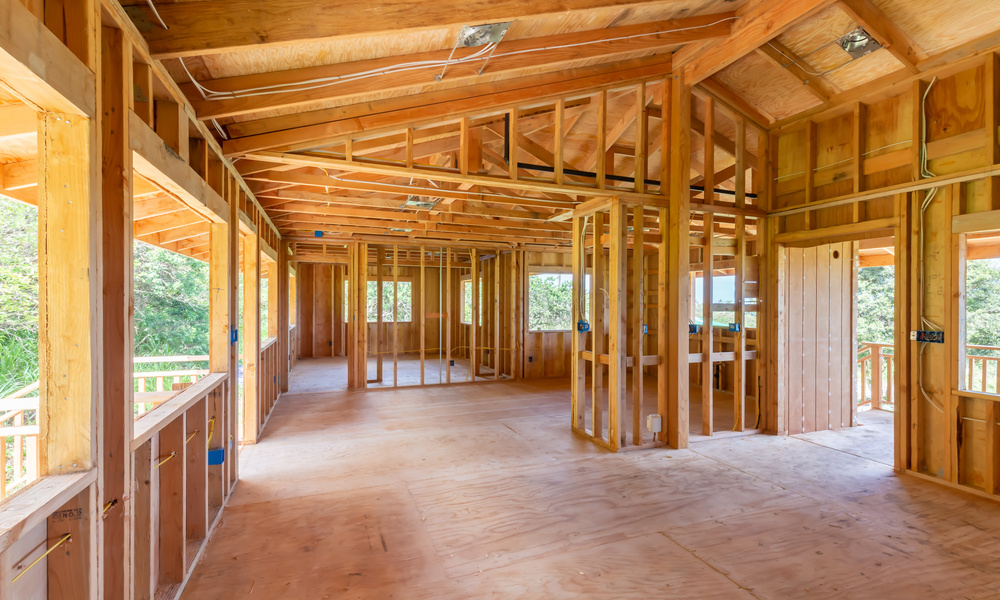 A custom home is in the beginning stages. There is wood, wiring, and planks, all exposed due to the lack of drywall.