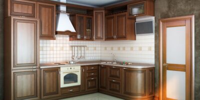 A newly remodeled kitchen with dark wooden cabinets, a tiled backsplash, a wall-mounted TV, and shiny flooring.