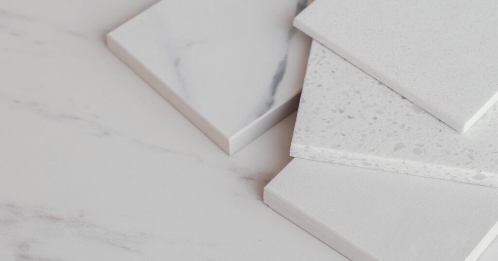 Various blocks of white stone samples with light gray marbling and texture spread out on a countertop.