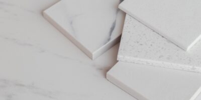 Various blocks of white stone samples with light gray marbling and texture spread out on a countertop.