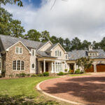 Driveway Materials: Which One's Right For You? A brown gravel driveway leading up to a very large home, which features warm colors and a combination of brick and siding.