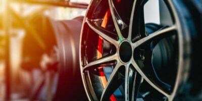 A wheel frame hanging on a shelf with other frames behind it. This wheel is meant for high-performance cars.