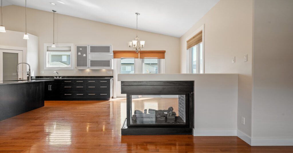 A large residential kitchen with black countertops. A small fireplace is prominently placed in the kitchen.