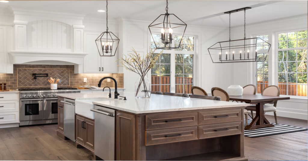 A kitchen in a traditional style luxury home, with quartz counters, hardwood floors, and new stainless steel appliances.