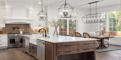 A kitchen in a traditional style luxury home, with quartz counters, hardwood floors, and new stainless steel appliances.