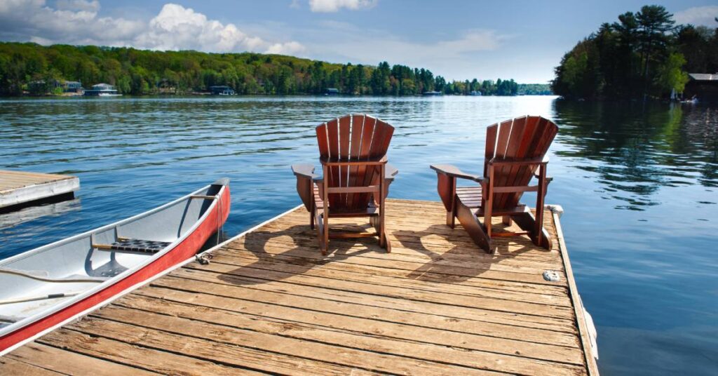 A peaceful dock with chairs set up to look over the clear water. There is also a small boat attached to the dock.