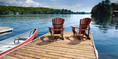 A peaceful dock with chairs set up to look over the clear water. There is also a small boat attached to the dock.