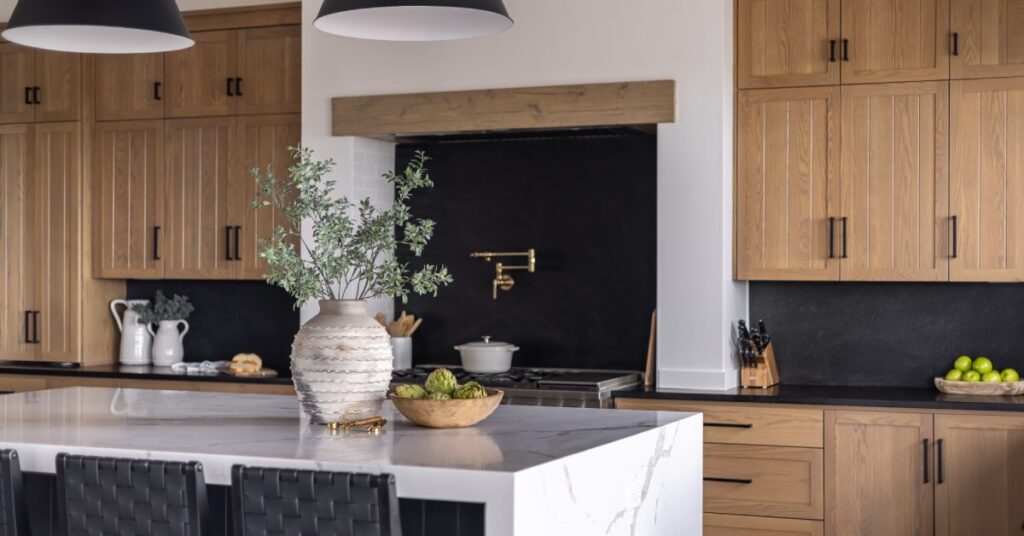 A modern kitchen with wooden cabinetry and black bar stools at the oversized marble kitchen island.