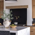 Outdated Design Trends and What To Replace Them With A modern kitchen with wooden cabinetry and black bar stools at the oversized marble kitchen island.