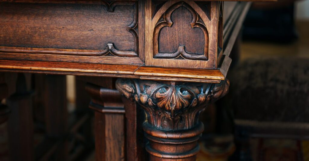 A close-up view of a carved wooden table corner with curved legs, a polished brown surface, and intricate designs.