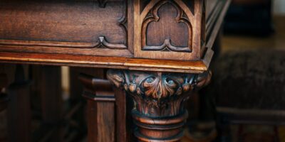 A close-up view of a carved wooden table corner with curved legs, a polished brown surface, and intricate designs.