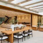 A luxury home with a large opening between the living room and outdoor living space. There is a lighted cover over the space.