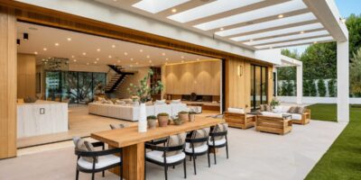 A luxury home with a large opening between the living room and outdoor living space. There is a lighted cover over the space.