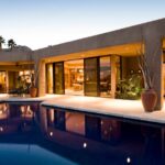 Design Principles That Create a More Sophisticated Backyard A close-up of the backyard space of a modern, minimalist-style home. There is a pool and two covered seating areas.