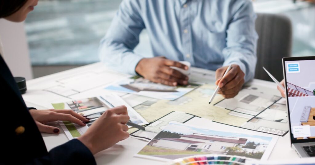 Two interior designers sit at the table to collaborate a home's design finishes, colors, and textures.