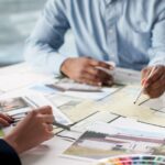 Timeless Materials Every Homeowner Should Consider Two interior designers sit at the table to collaborate a home's design finishes, colors, and textures.