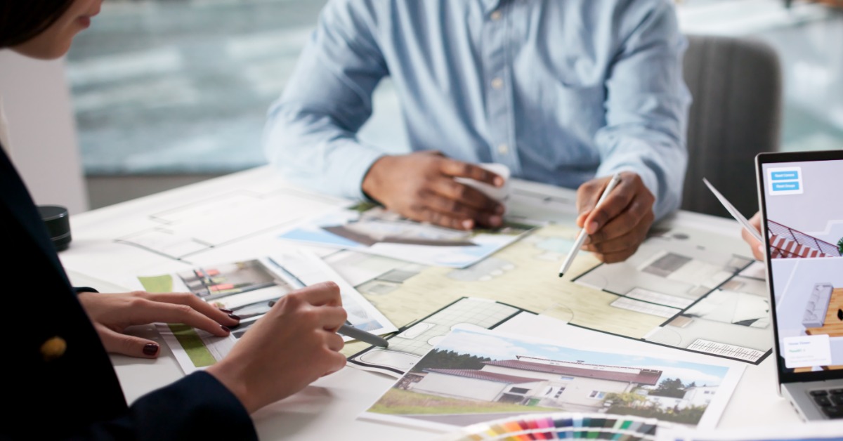 Two interior designers sit at the table to collaborate a home's design finishes, colors, and textures. Two interior designers sit at the table to collaborate a home's design finishes, colors, and textures.