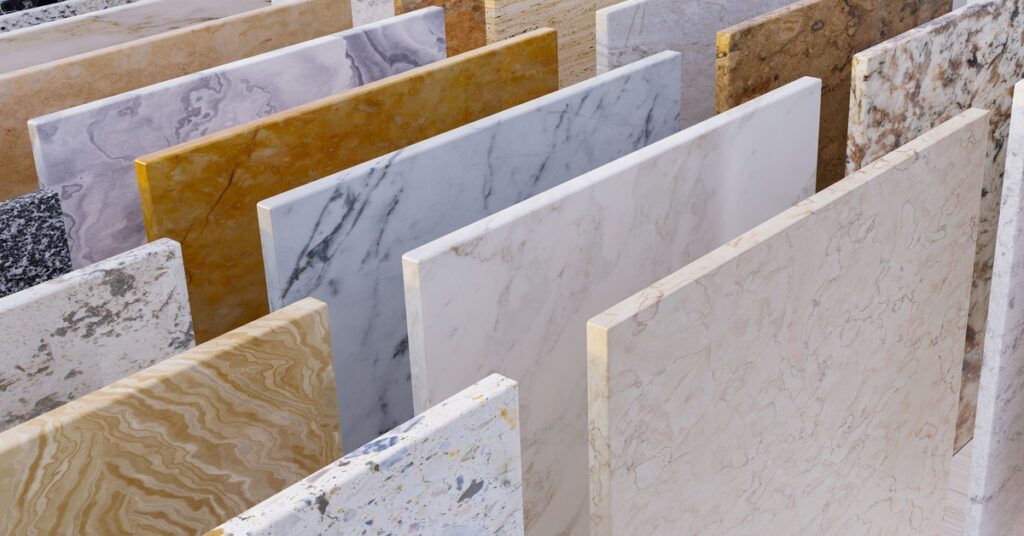 Rows of stone countertop and tile slabs in varied white, gray, tan, and gold patterns displayed upright.
