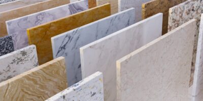 Rows of stone countertop and tile slabs in varied white, gray, tan, and gold patterns displayed upright.