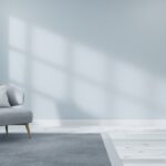 Must-Know Living Room Lighting Tips for Homeowners Sunlight shining through a window in a living room. The living room has light blue walls and a small light blue chair.