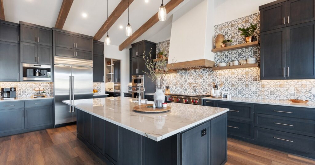 Luxury kitchen with dark cabinetry, marble island, patterned backsplash, wood floors, and exposed ceiling beams.